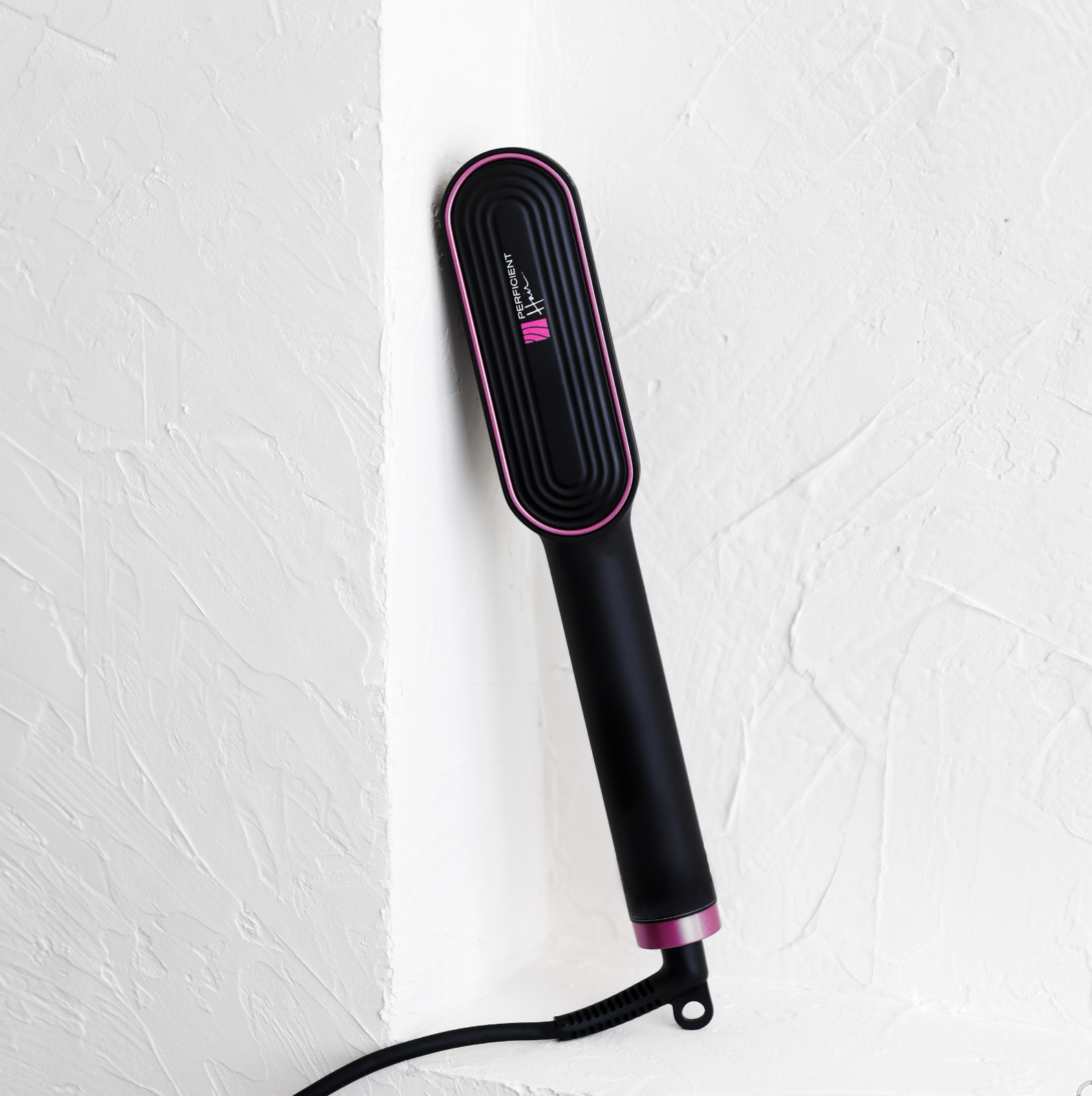 PH Ring Pro ionic hair straightening brush in matte black with magenta trim, styled against a white wall